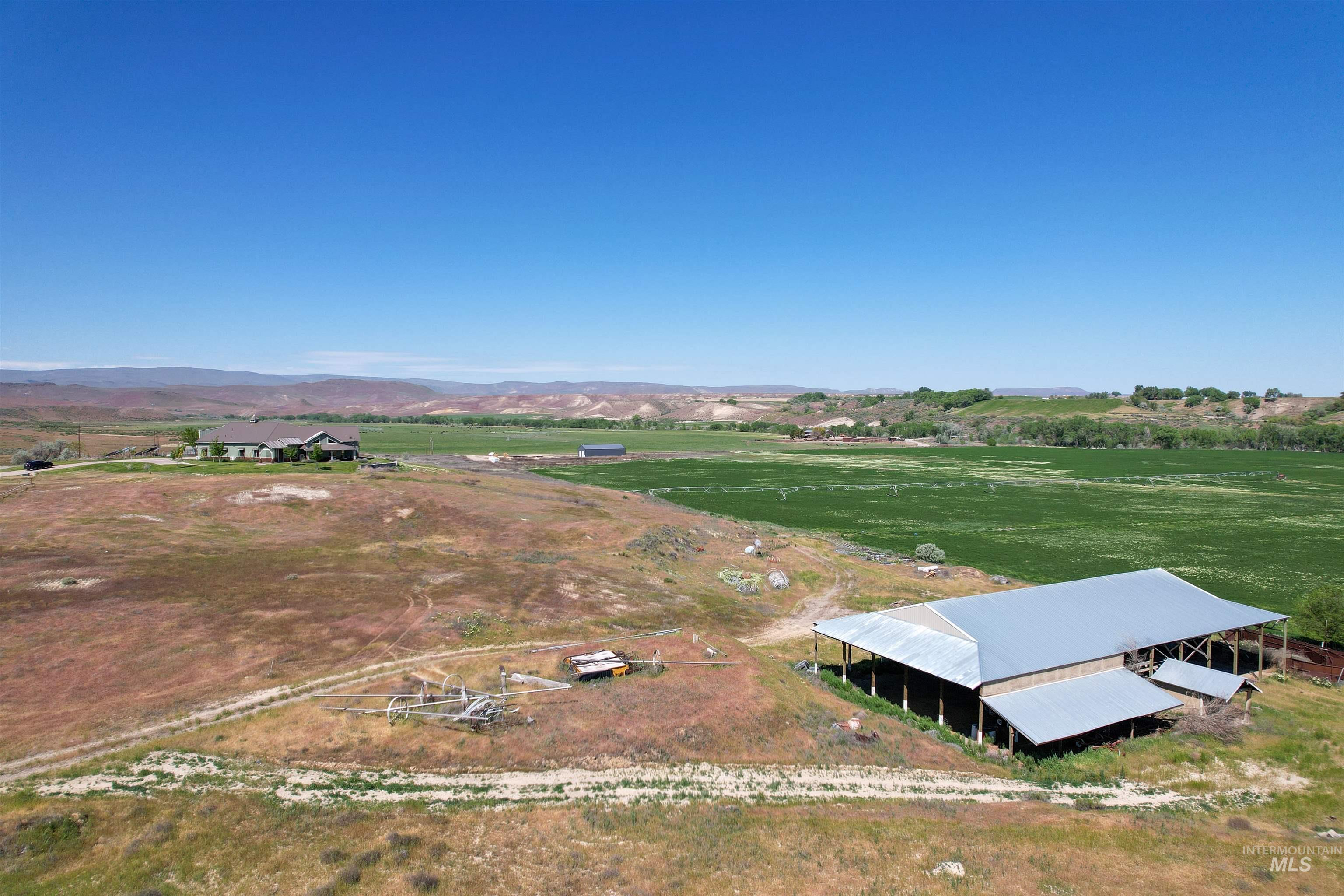 1030 Desert Glen Road Adrian, OR 97901 - Photo 11 of 47 Expansive rural property featuring multiple structures, including a main residence with a covered porch, a large barn with a corrugated metal roof, and a separate outbuilding