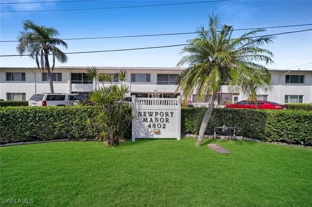 a sign board with flower plants and palm trees