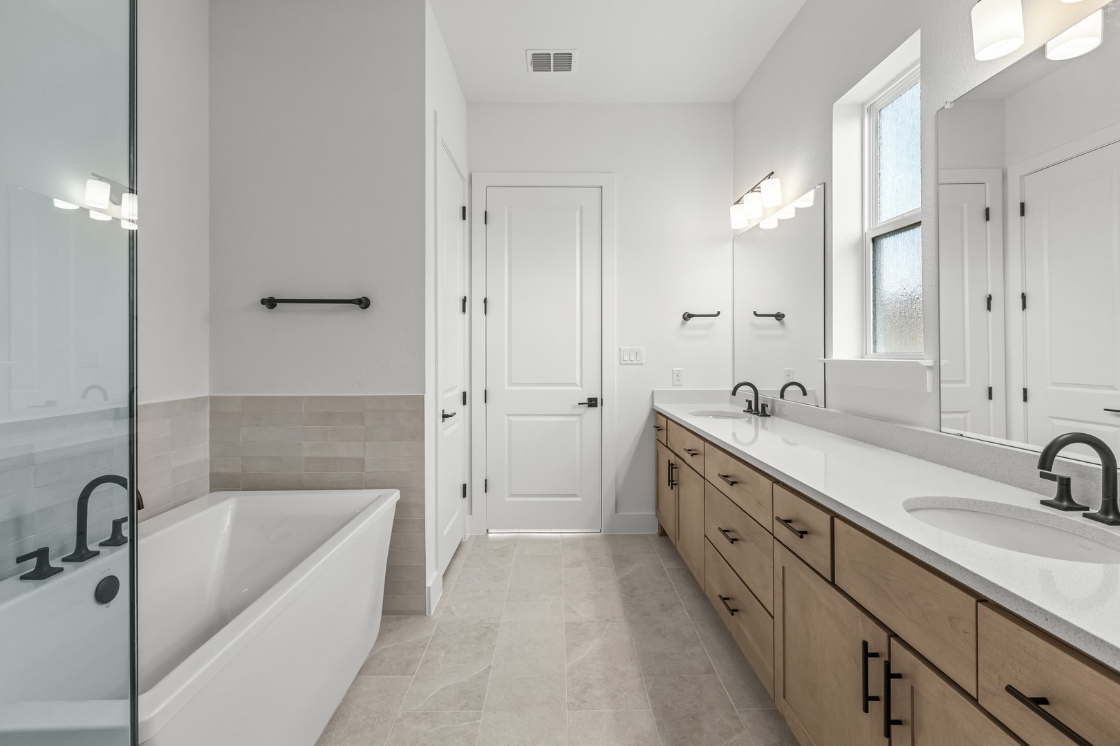 783 Iron Willow Loop Dripping Springs, TX 78620 - Photo 24 of 28 a bathroom with a tub sink double vanity granite tub shower and mirror