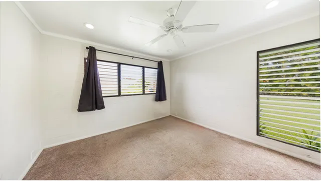 an empty room with windows and fan