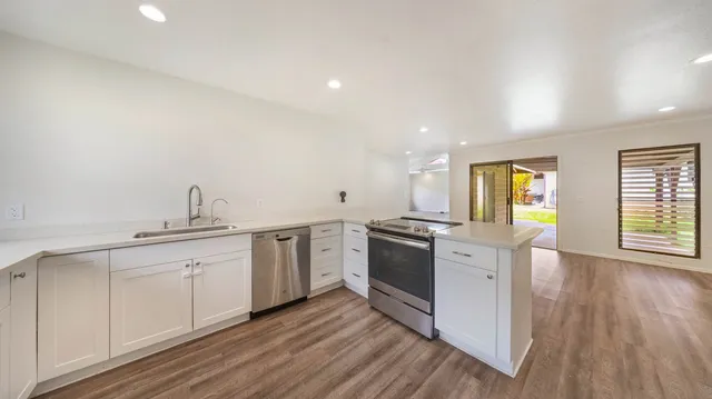a kitchen with granite countertop a sink cabinets and wooden floor