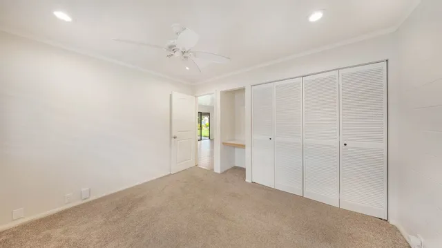 an empty room with a ceiling fan and closet area