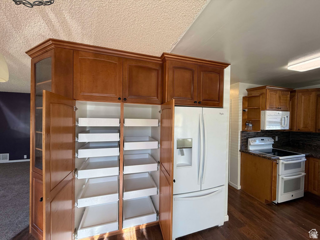 73 Garden Street Helper, UT 84526 - Photo 15 of 36 Kitchen featuring white appliances, wood finish cabinetry, backsplash, a textured ceiling, and dark wood finished floors