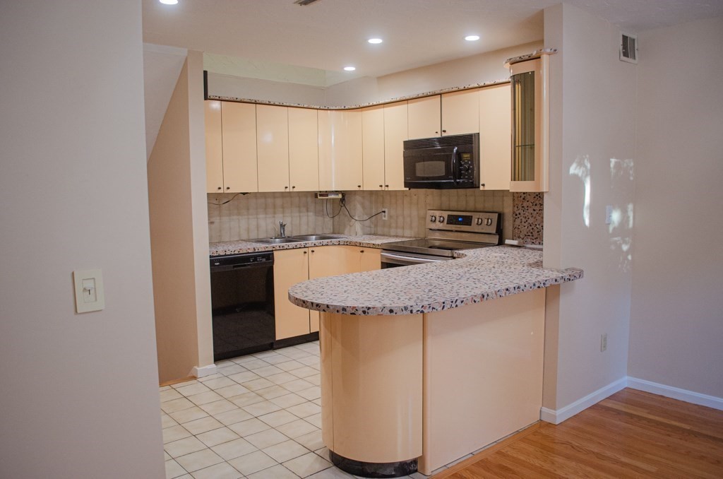 44 Regent Circle, Unit 44 Brookline, MA 02445 - Photo 7 of 10 a kitchen with granite countertop a sink and a stove top oven with wooden floor