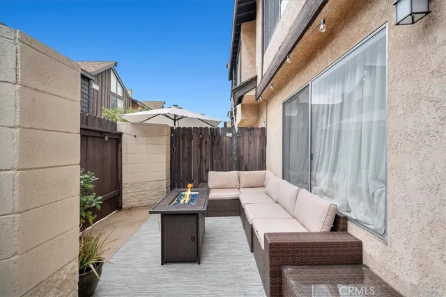 a view of a patio with couches and table and potted plants with wooden floor and wall