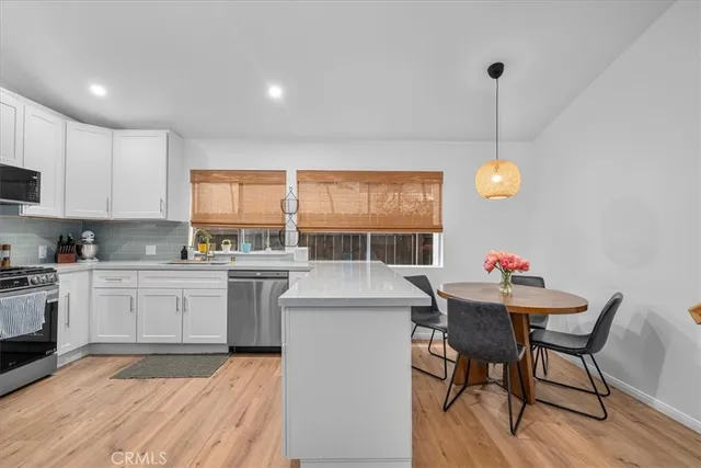 a kitchen with a stove a sink a dining table and chairs with wooden floor