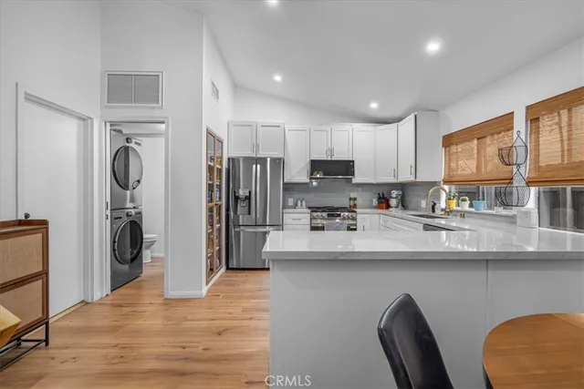 a kitchen with stainless steel appliances granite countertop a refrigerator a stove and a sink with wooden floor