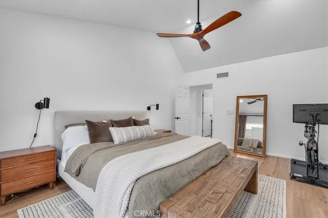 a bedroom with a bed a dresser and potted plants