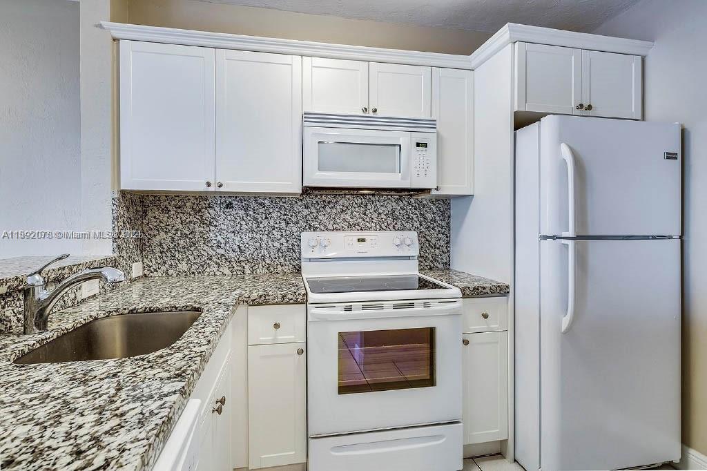 8305 Southwest 72nd Avenue, Unit 102A Miami, FL 33143 - Photo 1 of 18 a kitchen with a stove a refrigerator and a sink