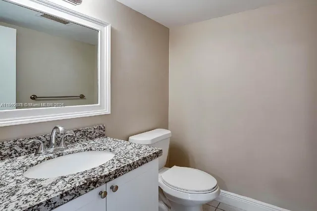 a bathroom with a granite countertop sink toilet and mirror