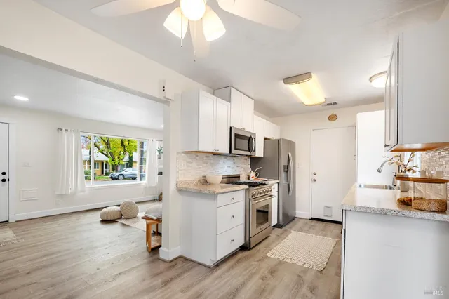 a kitchen with stainless steel appliances a stove top oven a sink dishwasher and a refrigerator with wooden floor