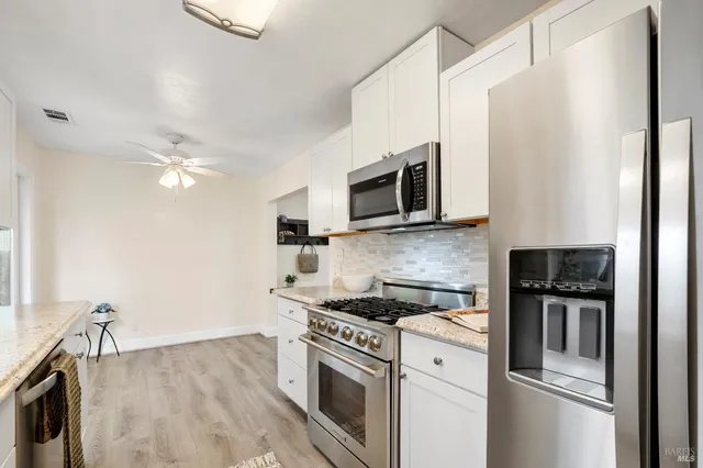 a kitchen with stainless steel appliances a stove a microwave and white cabinets