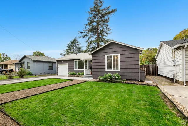 a front view of a house with a yard and trees