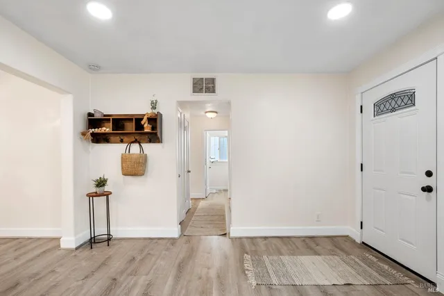 a view of a hallway with wooden floor and a bathroom