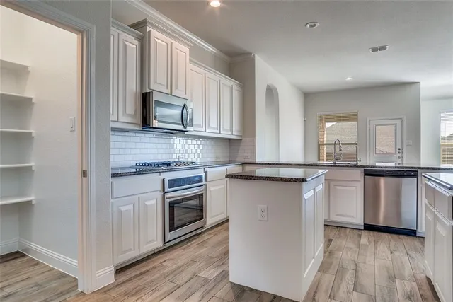 a kitchen with granite countertop a sink cabinets and stainless steel appliances