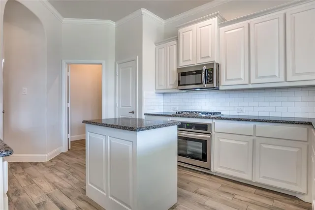 a kitchen with granite countertop white cabinets and stainless steel appliances