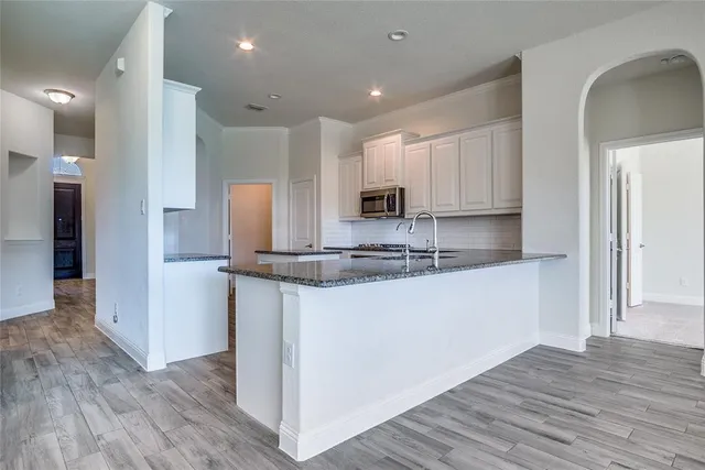 a kitchen with kitchen island granite countertop wooden cabinets and a sink