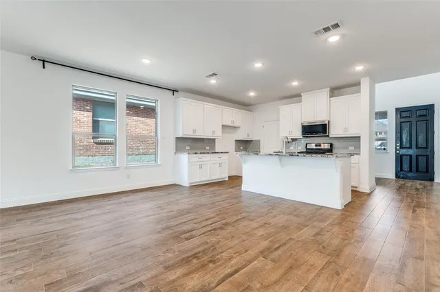 a view of kitchen with granite countertop stainless steel appliances refrigerator sink and cabinets