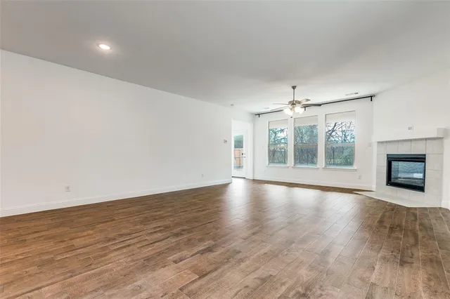 an empty room with wooden floor fireplace and windows