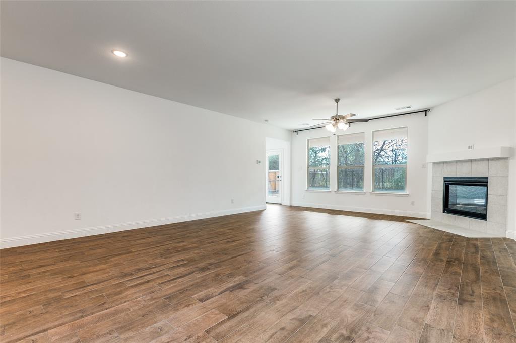 1400 Elizabeth Street Anna, TX 75409 - Photo 6 of 25 an empty room with wooden floor fireplace and windows