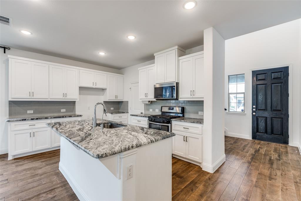 1400 Elizabeth Street Anna, TX 75409 - Photo 8 of 25 a kitchen with stainless steel appliances granite countertop a stove top oven a refrigerator a sink and dishwasher with wooden floor