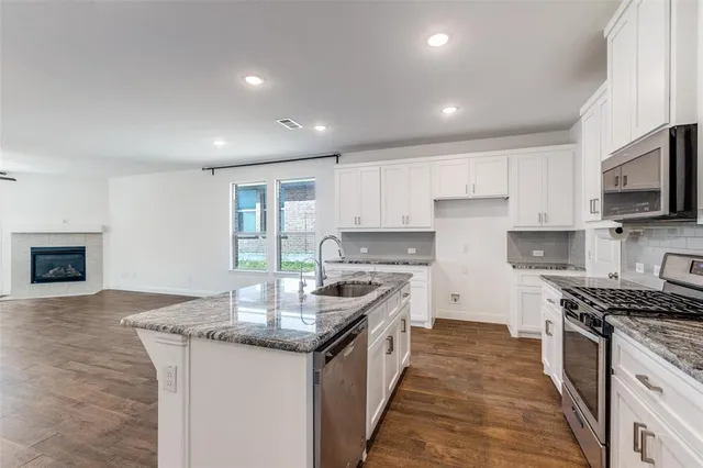 a kitchen with granite countertop stainless steel appliances a stove sink and microwave
