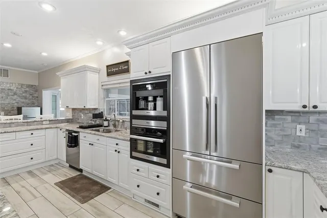 a large kitchen with granite countertop a large counter top appliances and cabinets