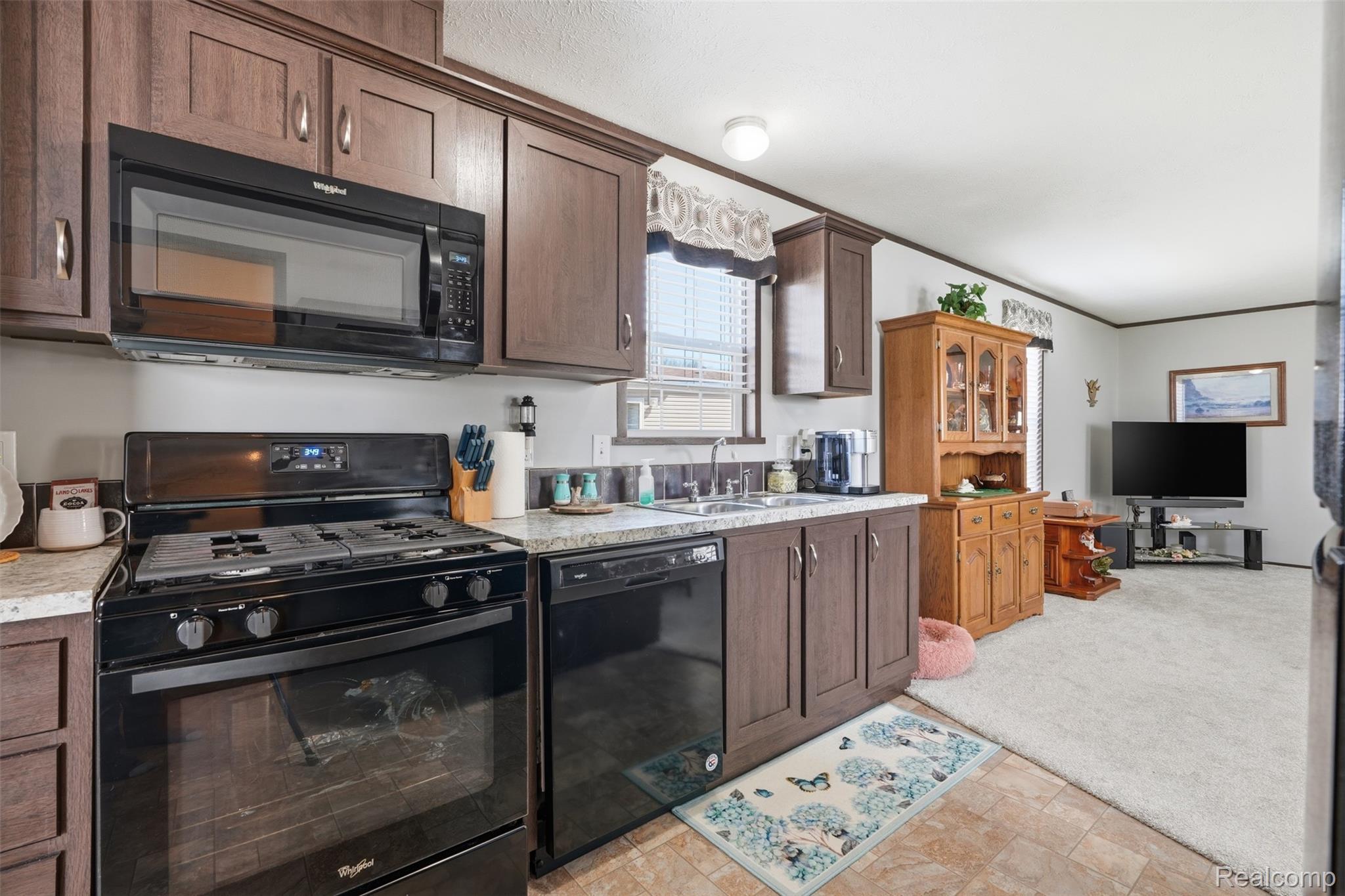440 Flamingo Street Rochester, MI 48309 - Photo 16 of 32 Kitchen with black appliances, light countertops, crown molding, dark wood finish cabinets, and light carpet