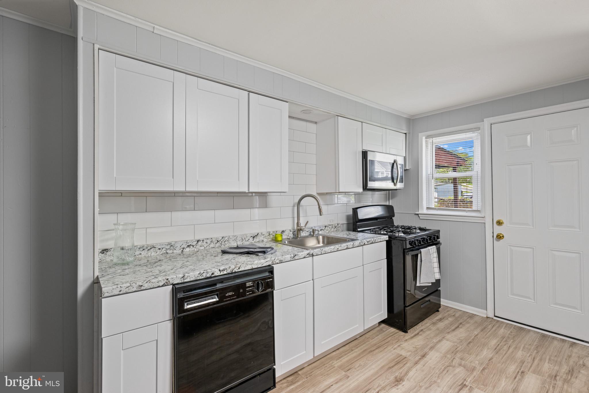 301 3rd Street Baltimore, MD 21206 - Photo 13 of 25 a kitchen with stainless steel appliances granite countertop a stove sink and cabinets
