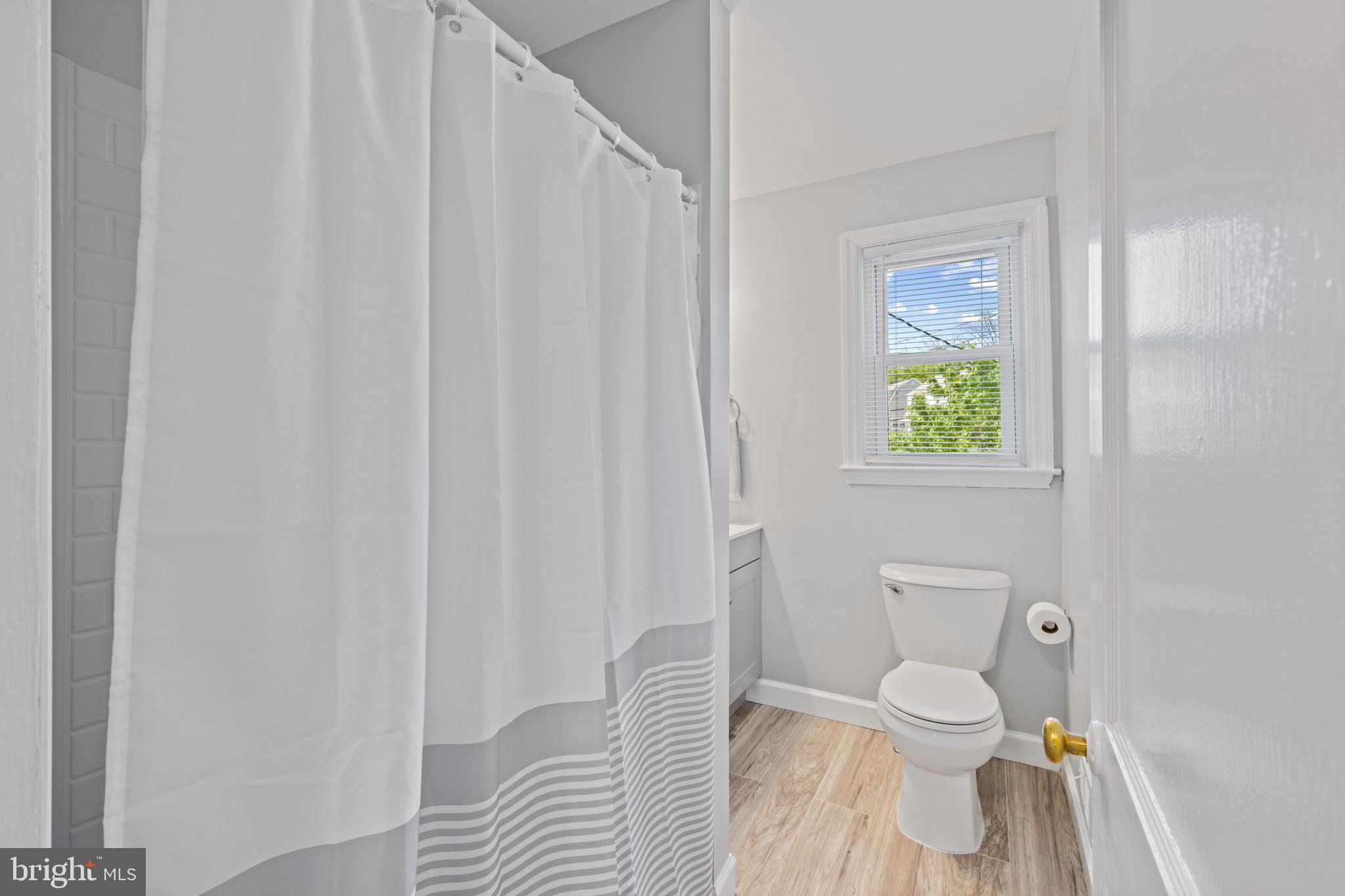 301 3rd Street Baltimore, MD 21206 - Photo 19 of 25 a white toilet sitting next to a shower curtain