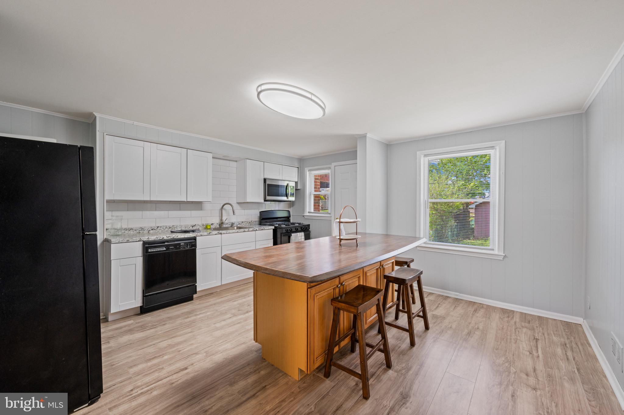 301 3rd Street Baltimore, MD 21206 - Photo 10 of 25 a kitchen with kitchen island granite countertop wooden floors and stainless steel appliances
