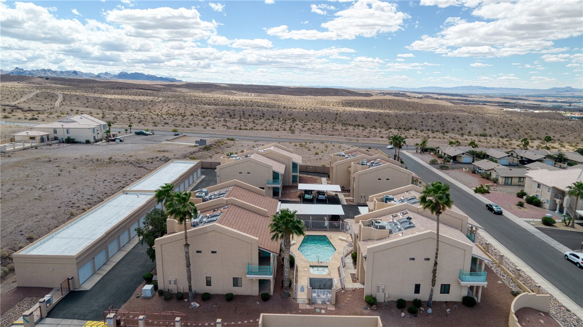 Aerial view of the property, showcasing a swimming pool, multiple residential buildings with terracotta-style roofs, and palm trees