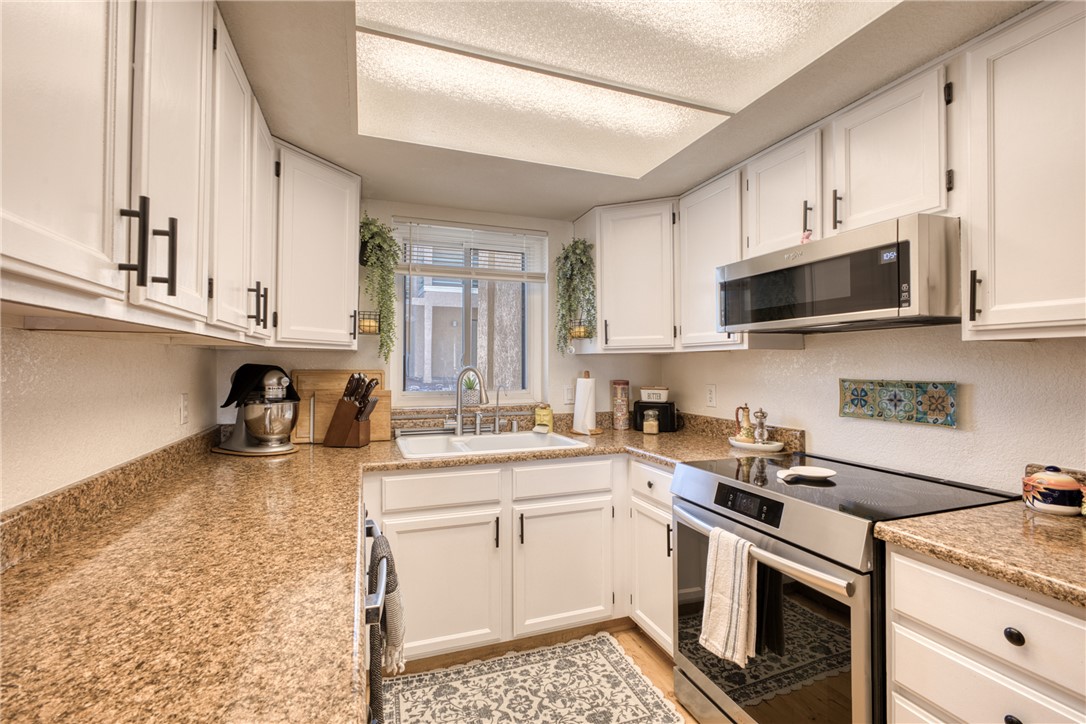3400 Sunriver Road, Unit D2 Bullhead City, AZ 86429 - Photo 12 of 61 The kitchen features white cabinetry with contrasting dark hardware, a stainless steel microwave, and a stainless steel oven with a flat cooktop