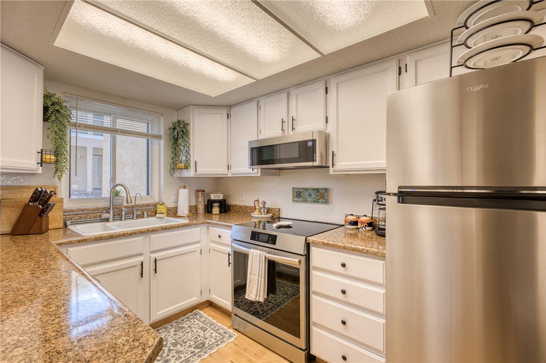 3400 Sunriver Road, Unit D2 Bullhead City, AZ 86429 - Photo 13 of 61 The kitchen features white cabinetry, granite countertops, a stainless steel refrigerator, and a built-in microwave