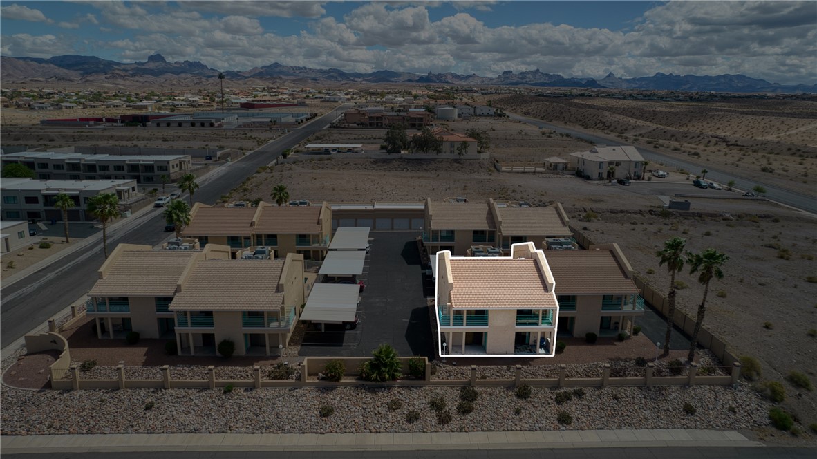 3400 Sunriver Road, Unit D2 Bullhead City, AZ 86429 - Photo 2 of 61 The property features a two-story structure with balconies, set within a community with desert landscaping and distant mountain views