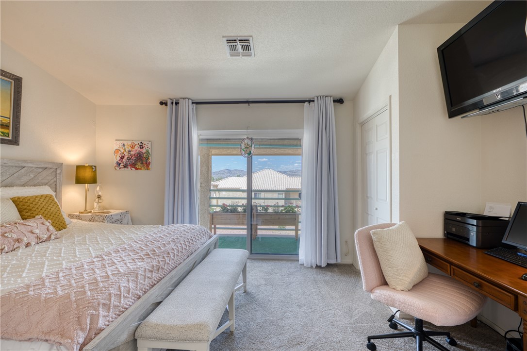 3400 Sunriver Road, Unit D2 Bullhead City, AZ 86429 - Photo 18 of 61 This bedroom features neutral-toned carpeting and a sliding glass door leading to a balcony, providing views of distant hills