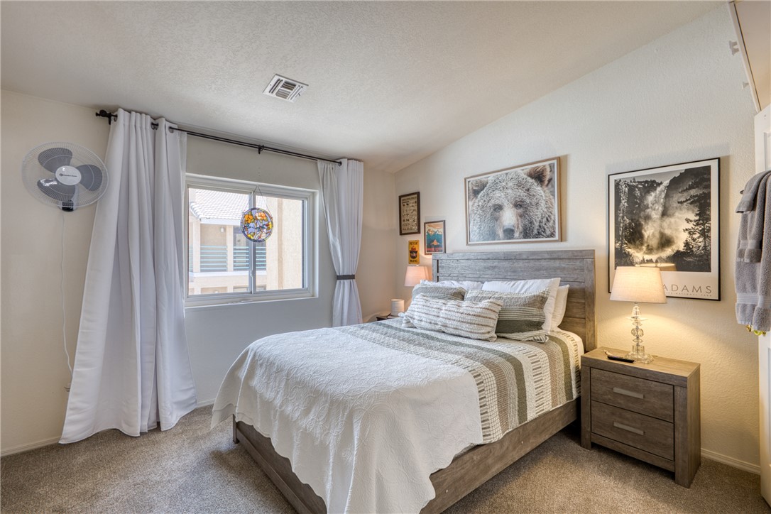 3400 Sunriver Road, Unit D2 Bullhead City, AZ 86429 - Photo 27 of 61 This bedroom features carpeted flooring, a window with curtains, and a bed with a wooden headboard