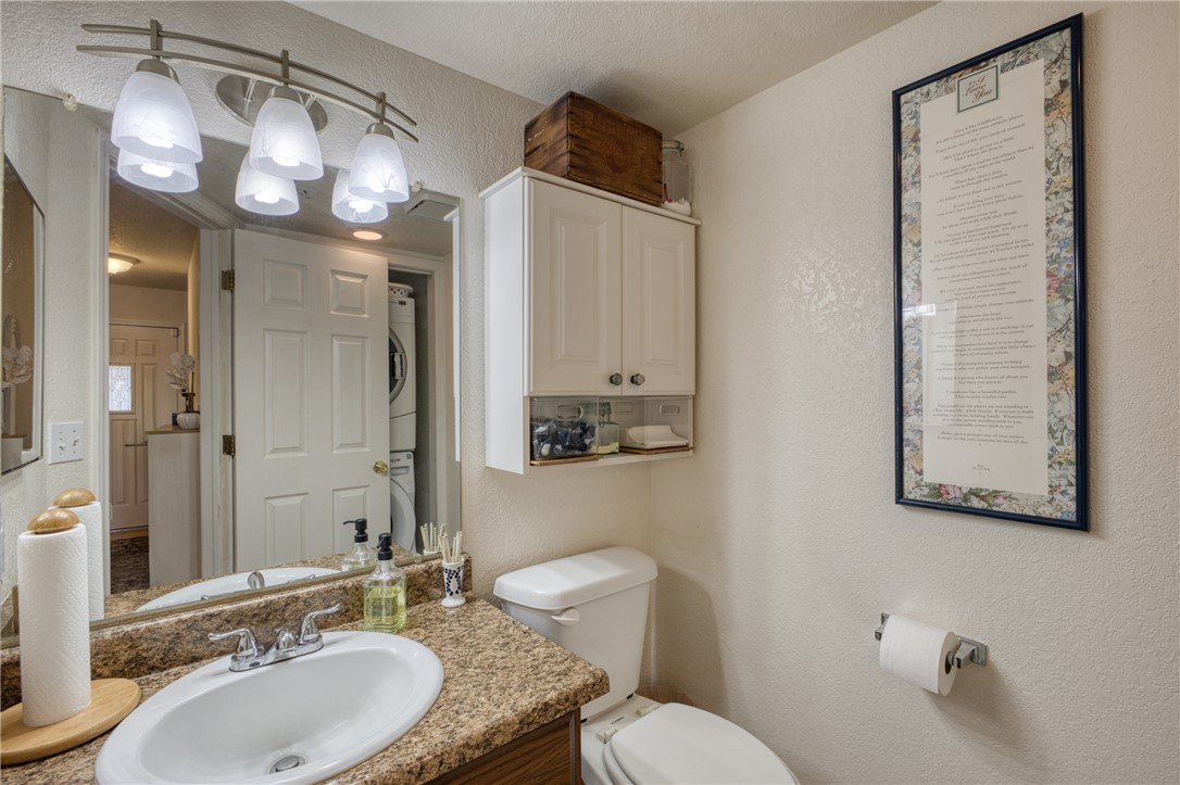 3400 Sunriver Road, Unit D2 Bullhead City, AZ 86429 - Photo 29 of 61 The property includes a bathroom with a vanity featuring a granite countertop and an oval sink, a wall-mounted light fixture with frosted glass shades, and a white toilet
