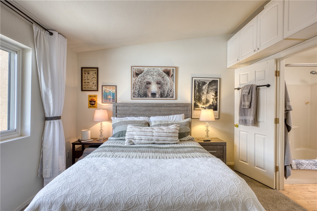 3400 Sunriver Road, Unit D2 Bullhead City, AZ 86429 - Photo 32 of 61 This room features a window with white curtains, a bed with a wooden headboard, and overhead storage cabinets