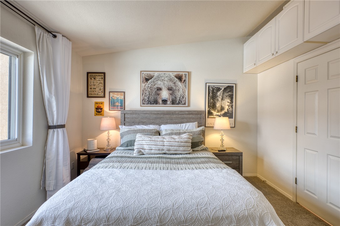 3400 Sunriver Road, Unit D2 Bullhead City, AZ 86429 - Photo 33 of 61 This bedroom features a light-colored wood headboard, a window with white curtains, and carpeted flooring
