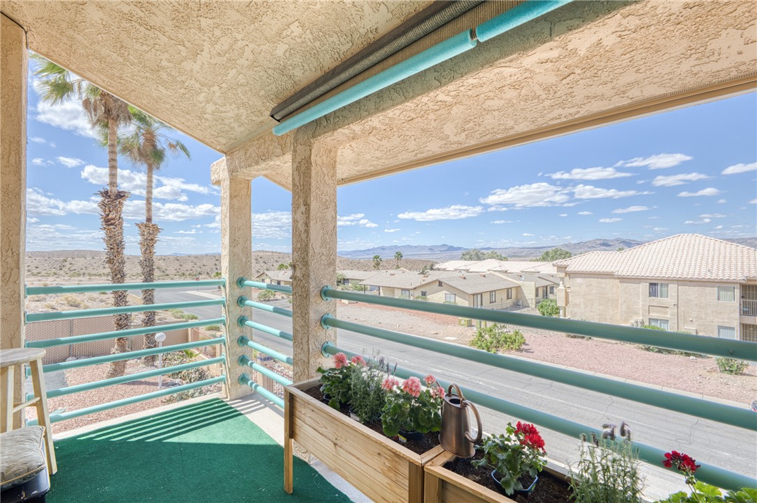 3400 Sunriver Road, Unit D2 Bullhead City, AZ 86429 - Photo 41 of 61 The property features a balcony with a partial view of palm trees and distant mountains, as well as views of residential buildings and a street