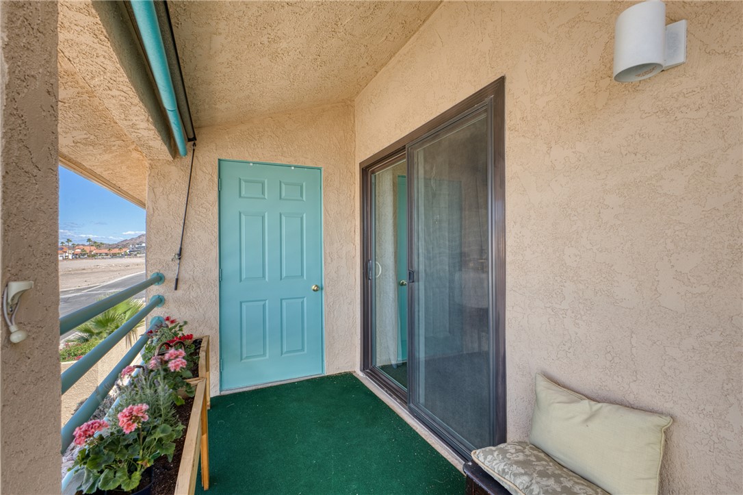 3400 Sunriver Road, Unit D2 Bullhead City, AZ 86429 - Photo 42 of 61 The property features a balcony with textured exterior walls, a light blue entry door, and a sliding glass door