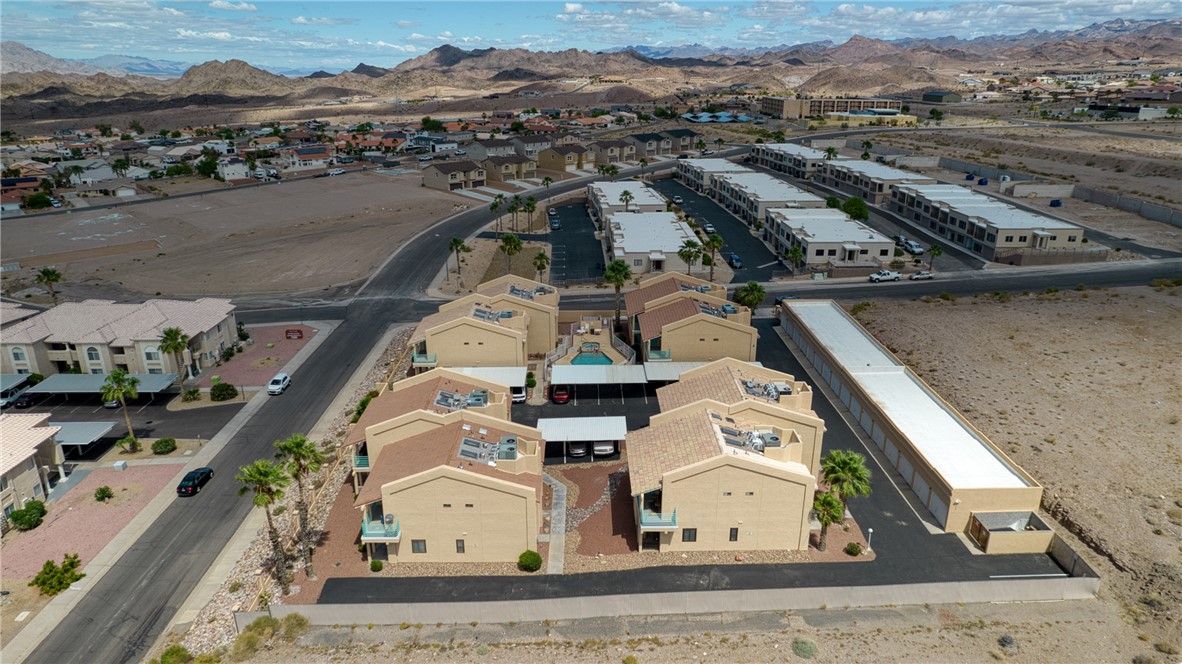 3400 Sunriver Road, Unit D2 Bullhead City, AZ 86429 - Photo 53 of 61 Aerial view showcasing properties with light-colored exteriors and tile roofs, surrounded by landscaped areas with palm trees