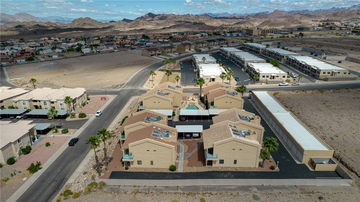 3400 Sunriver Road, Unit D2 Bullhead City, AZ 86429 - Photo 54 of 61 Aerial view of the property and its surrounding area, featuring a central courtyard with a swimming pool, covered parking, and mountain views in the distance