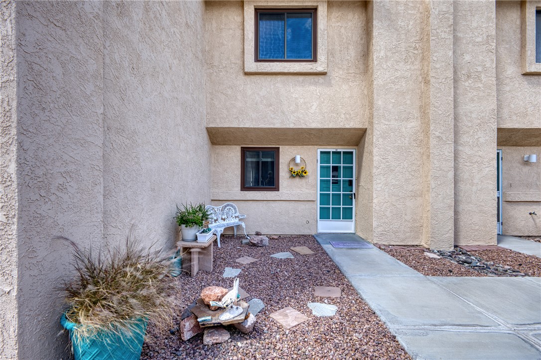 3400 Sunriver Road, Unit D2 Bullhead City, AZ 86429 - Photo 55 of 61 The property features a stucco exterior, a turquoise paneled front door, and a rock garden with decorative pavers