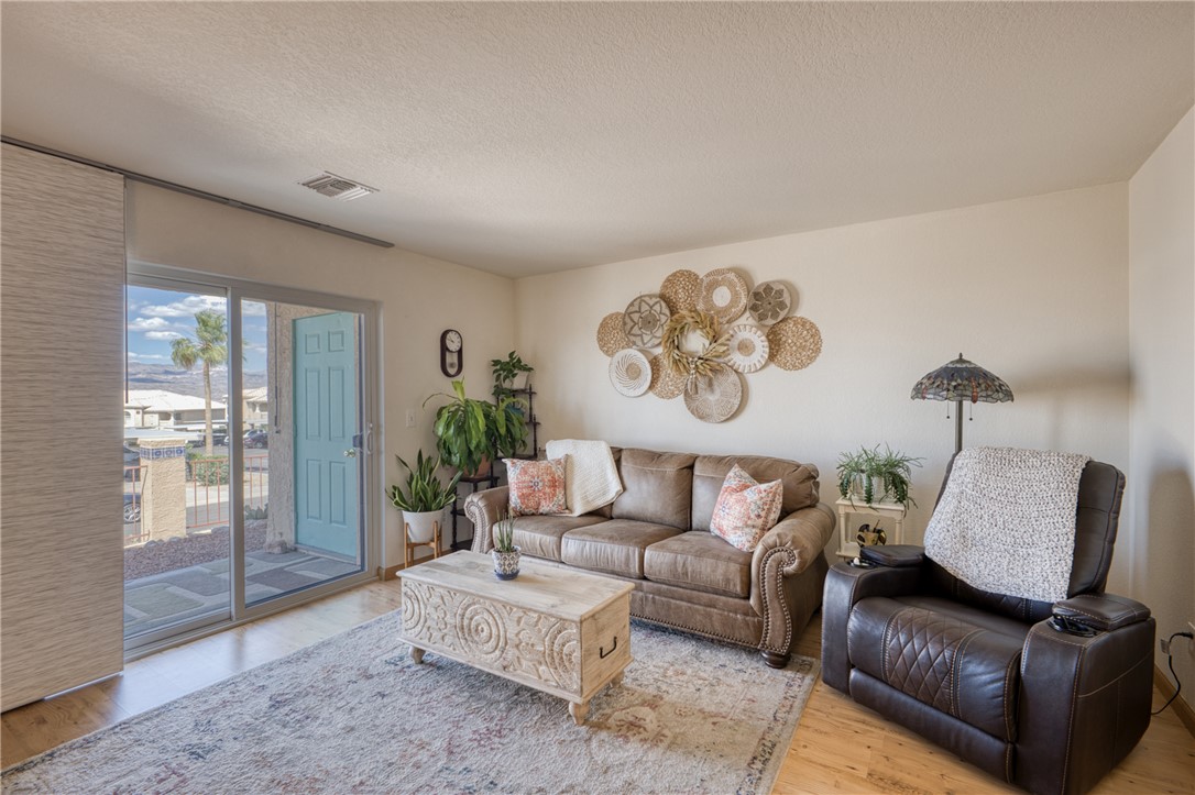 3400 Sunriver Road, Unit D2 Bullhead City, AZ 86429 - Photo 5 of 61 Living room with a sliding glass door and a view of the exterior, featuring a light blue front door, and a partially visible palm tree