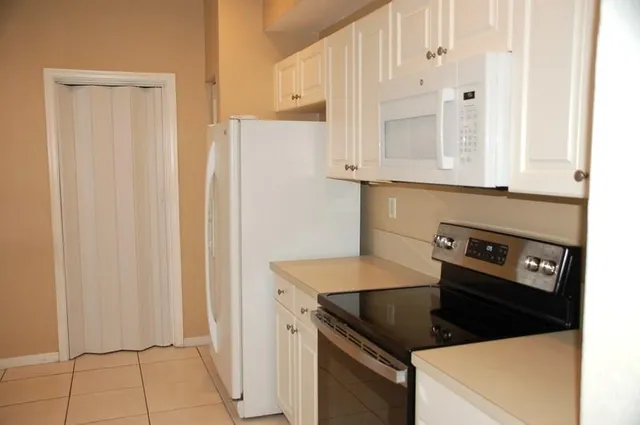 a kitchen with white cabinets and white appliances