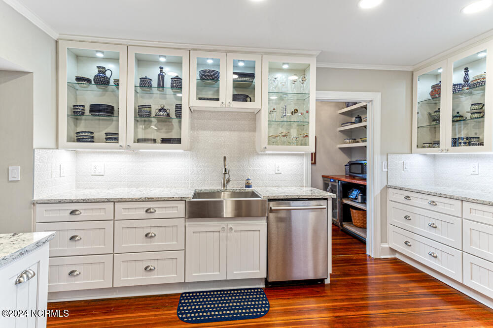 180 North Ridge Street Southern Pines, NC 28387 - Photo 32 of 72 Complete kitchen renovation with custom cabinetry with lighted glass upper cabinets, farm sink, Cambria quartz countertops, under cabinet lighting, and porcelain tile backsplash.