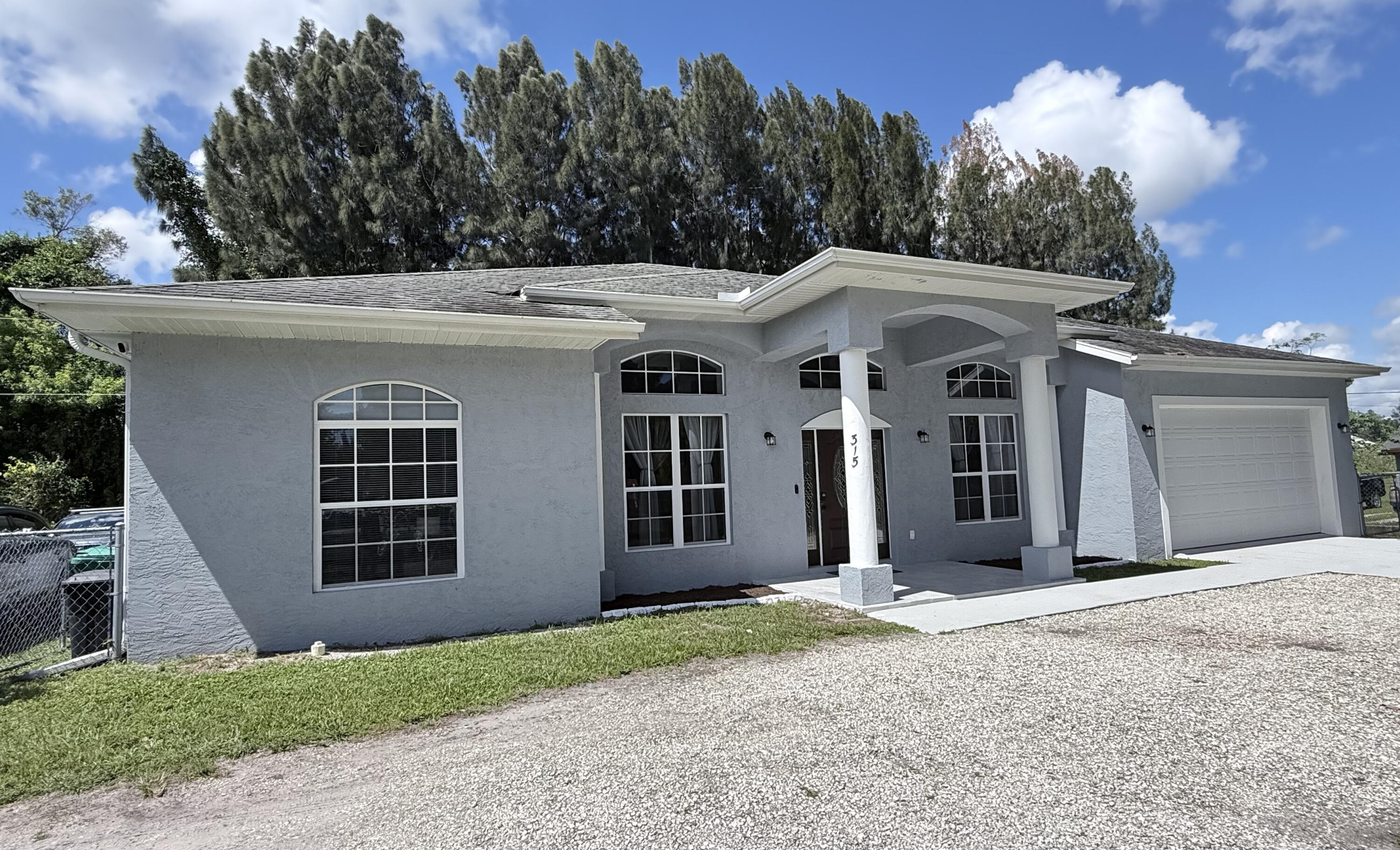 315 Kaye Street Fort Pierce, FL 34947 - Photo 3 of 66 a view of a white house with large windows and a small yard