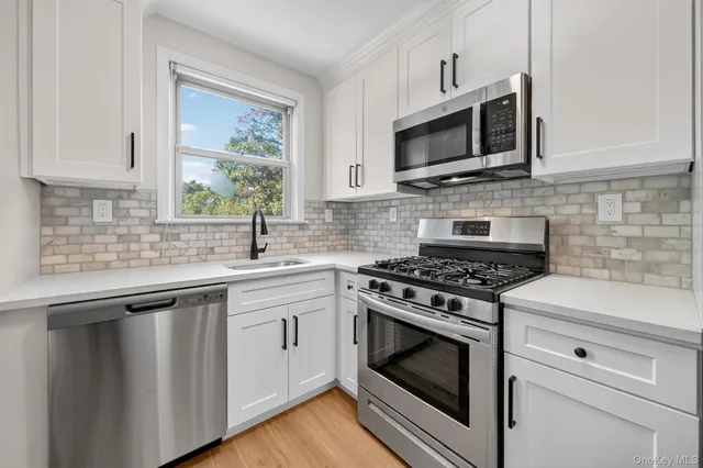 a kitchen with stainless steel appliances white cabinets granite counter tops and a window